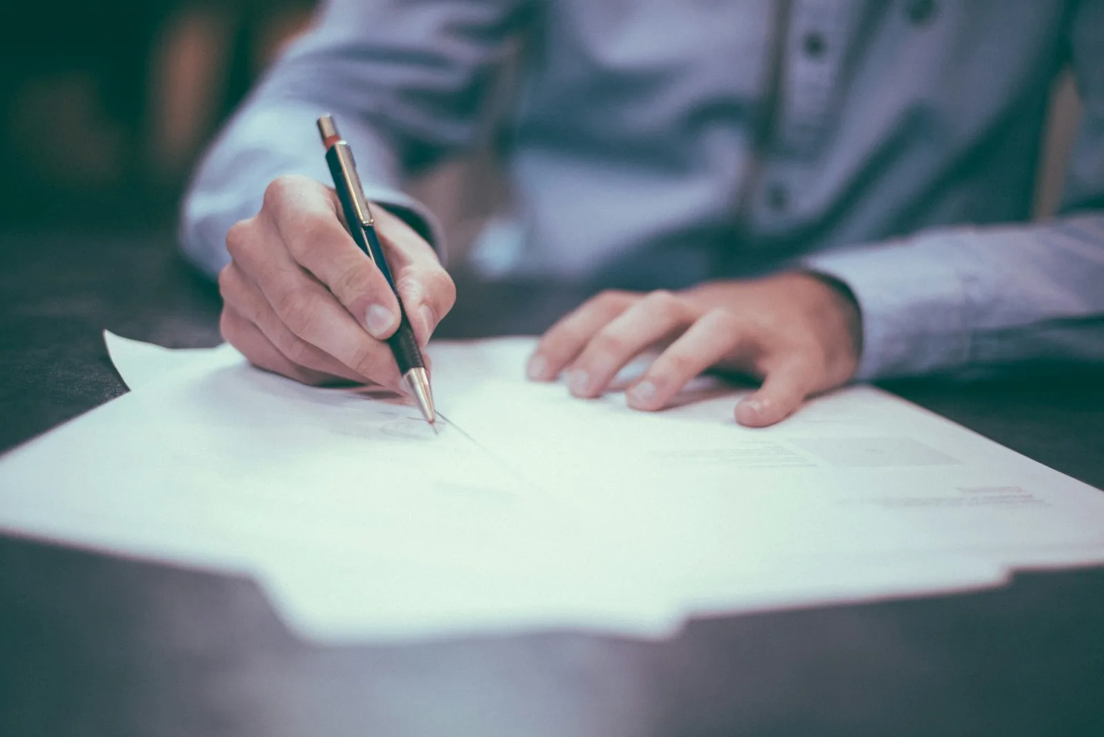 An investor signing a multi-page agreement at a conference table